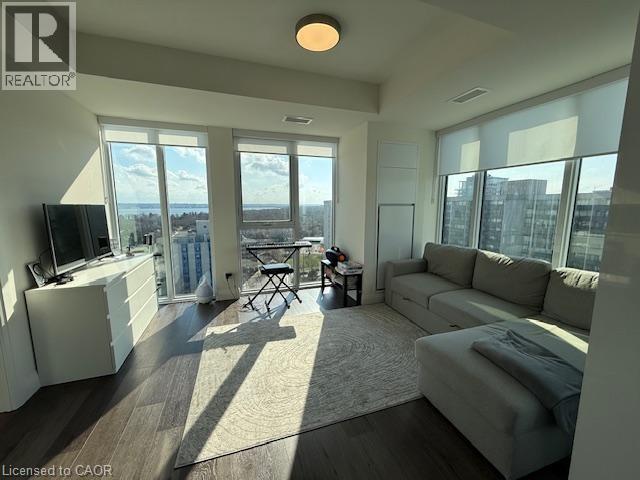 Bright living space featuring large windows with city and water views, hardwood floors, and a ceiling light fixture