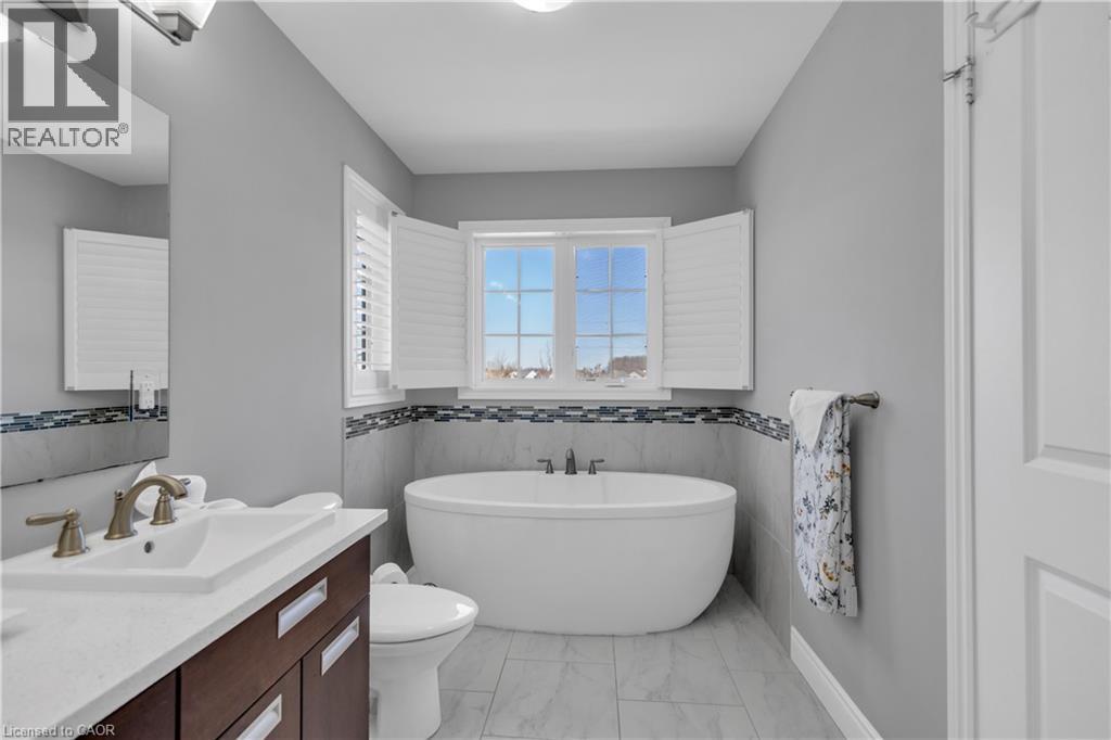 Bathroom featuring a freestanding bathtub, a window with white shutters, a vanity with a white countertop and dark wood cabinetry, and a mosaic tile backsplash