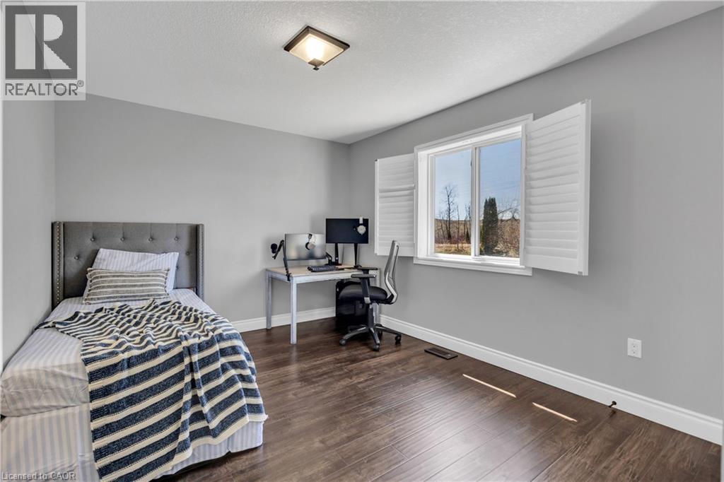 This room features hardwood flooring, light grey walls, and a window with white shutters