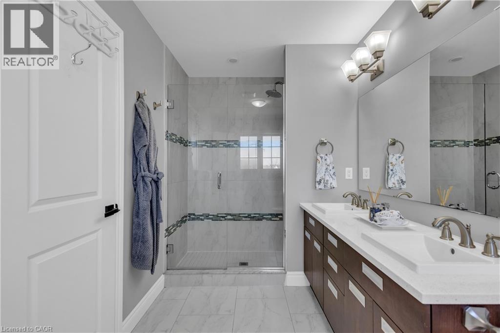 Bathroom with double vanity, a stall shower, and light marble finish flooring