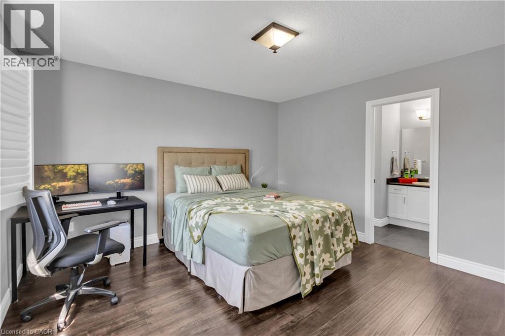 Bedroom featuring an office area, dark wood-style floors, and ensuite bathroom