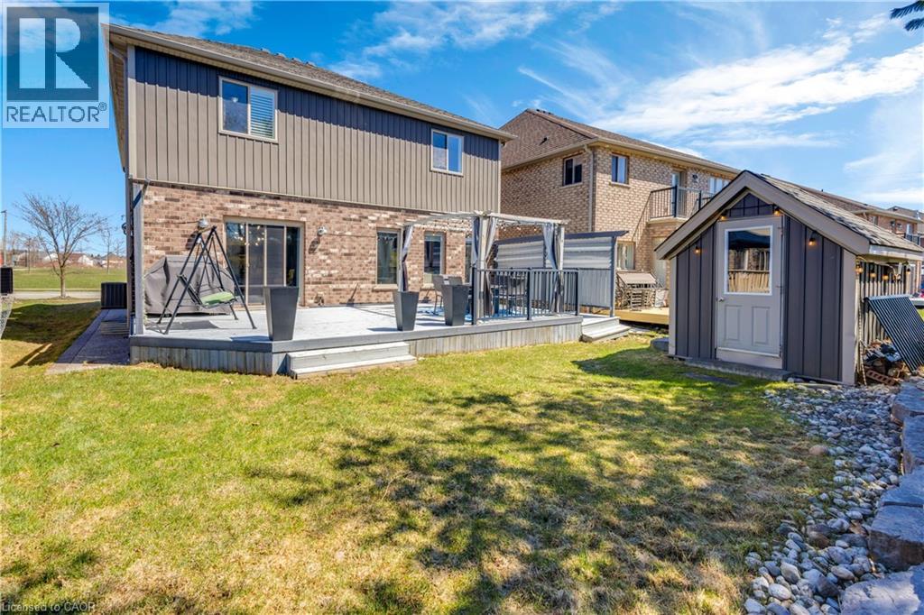 Back of property with a wooden deck, brick siding, board and batten siding, a yard, and a shed