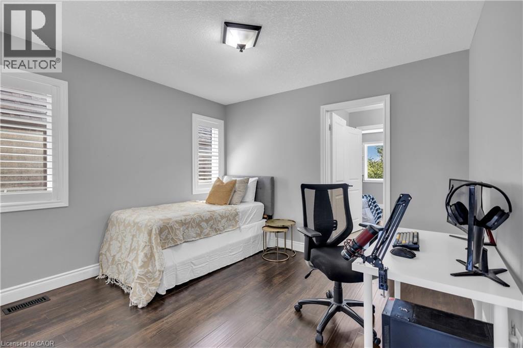 Bedroom with a textured ceiling, dark wood-style flooring, and a desk