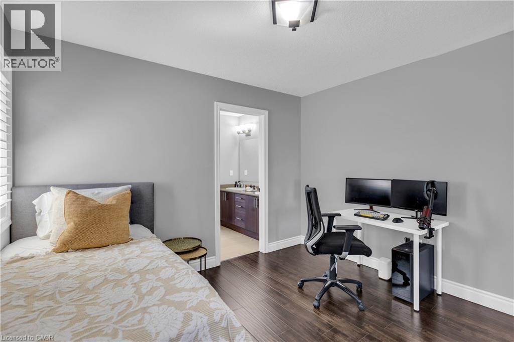 Bedroom with a desk, dark wood-style flooring, and ensuite bath