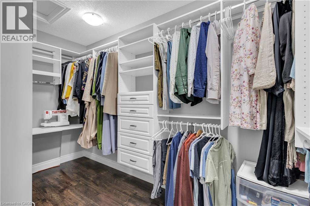 Walk in closet featuring attic access and dark wood finished floors