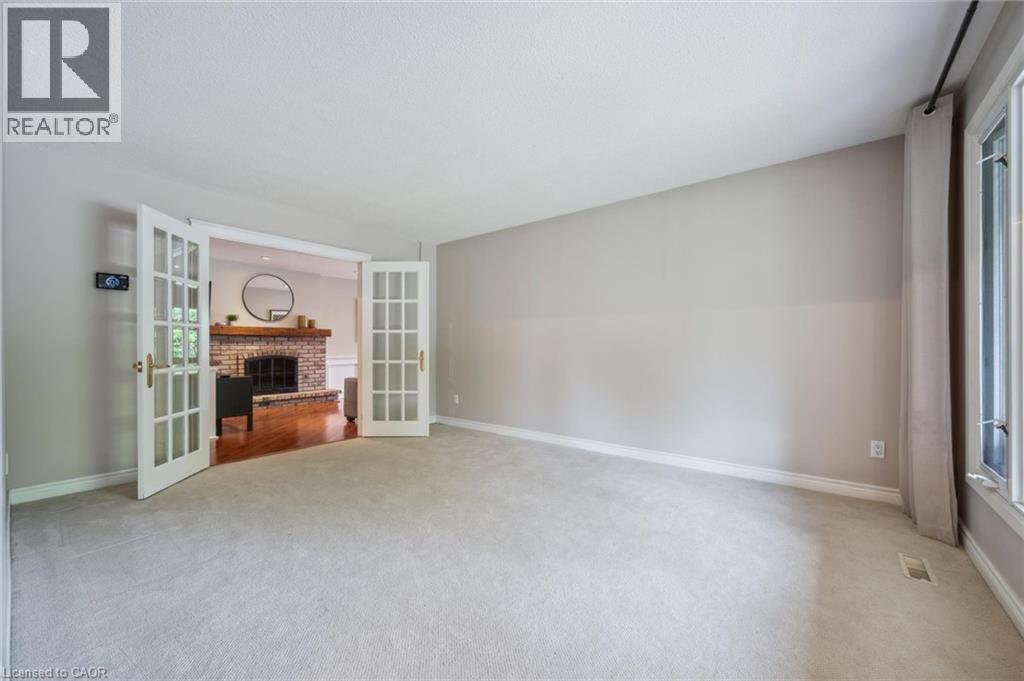 Unfurnished living room featuring a brick fireplace, french doors, light colored carpet, and healthy amount of natural light