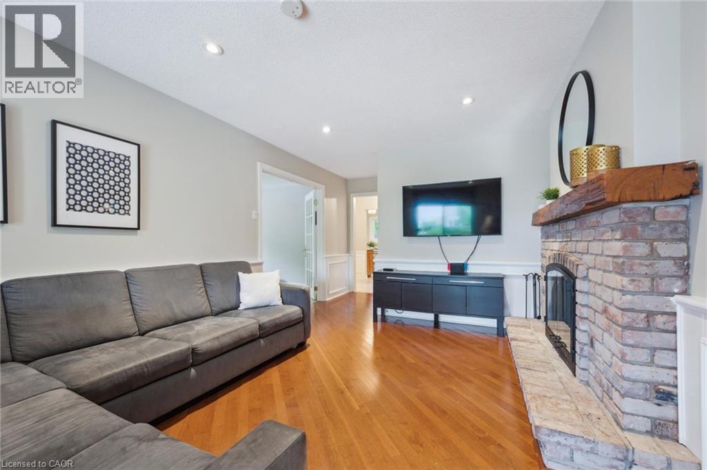 Living room with wainscoting, light wood-style floors, a brick fireplace, a decorative wall, and recessed lighting