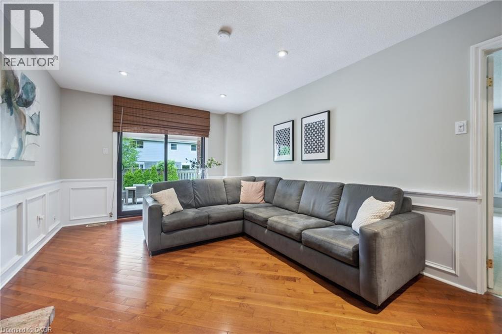 Living room with a wainscoted wall, a decorative wall, light wood finished floors, and a textured ceiling