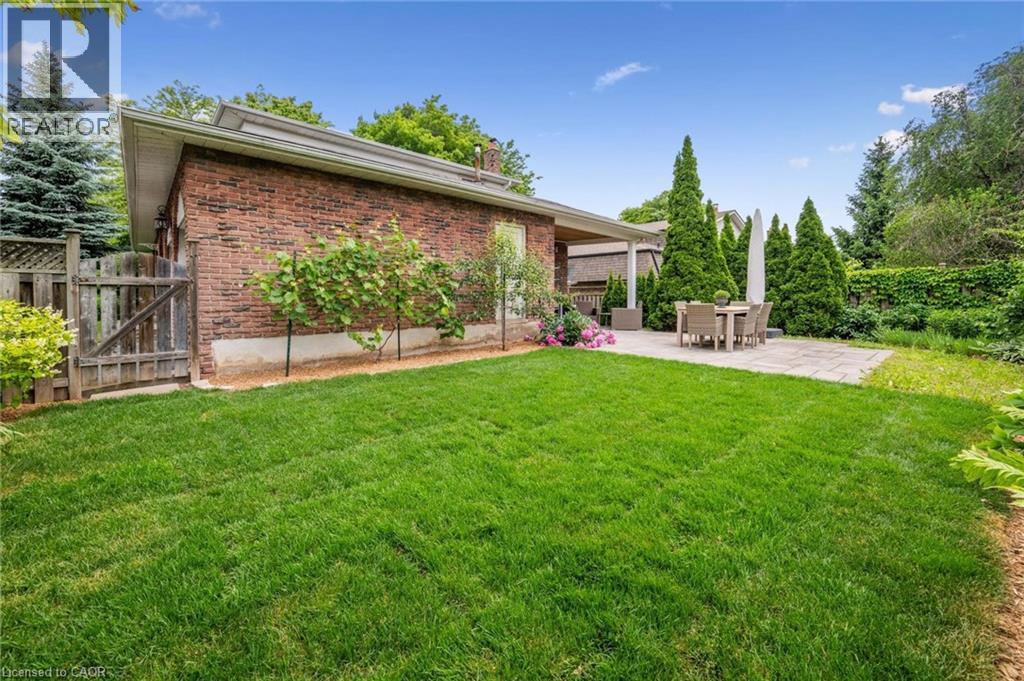 Rear view of house with brick siding, a patio area, a chimney, a gate, and outdoor dining space