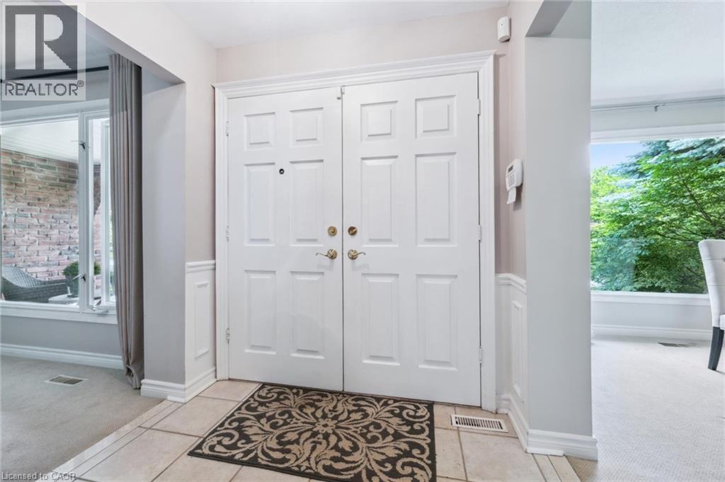 Foyer with light colored carpet, healthy amount of natural light, a wainscoted wall, and light tile patterned floors