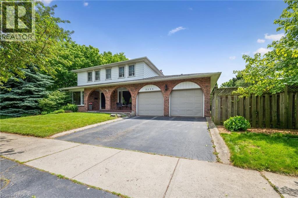 Traditional-style house with an attached garage, a porch, asphalt driveway, and brick siding