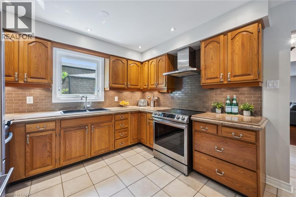 Kitchen featuring wood finish cabinets, stainless steel range with electric stovetop, light tile patterned floors, light stone counters, and recessed lighting