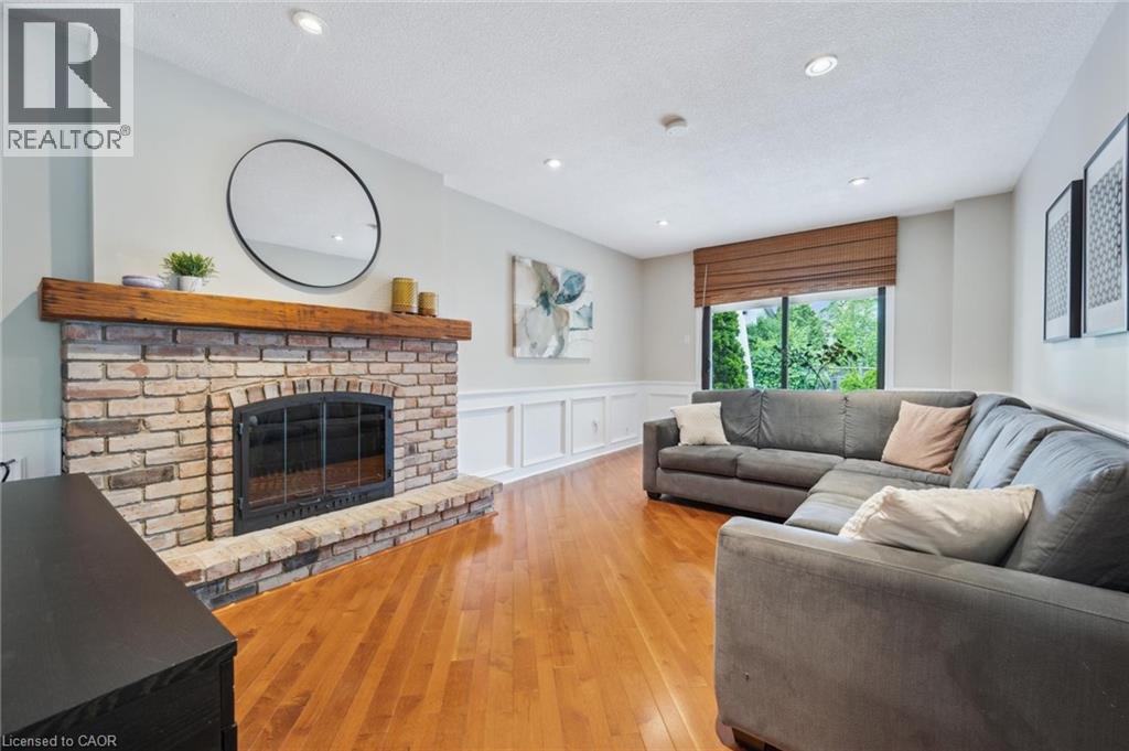 Living room featuring a decorative wall, a wainscoted wall, light wood-type flooring, a brick fireplace, and recessed lighting