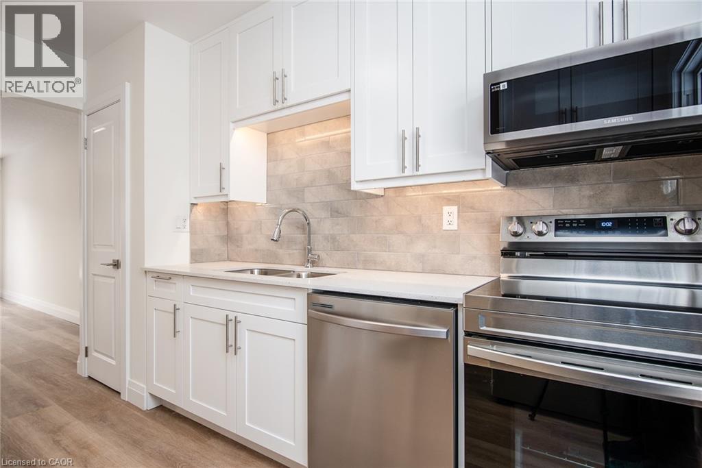 Kitchen with stainless steel appliances, white cabinetry, light wood finished floors, and light stone countertops