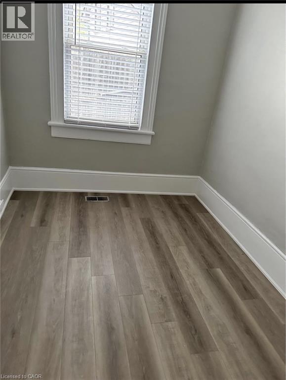 Room with wood-style flooring and a window featuring blinds