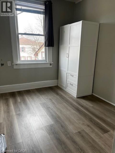 The room features plank flooring, painted walls, and a window with blinds