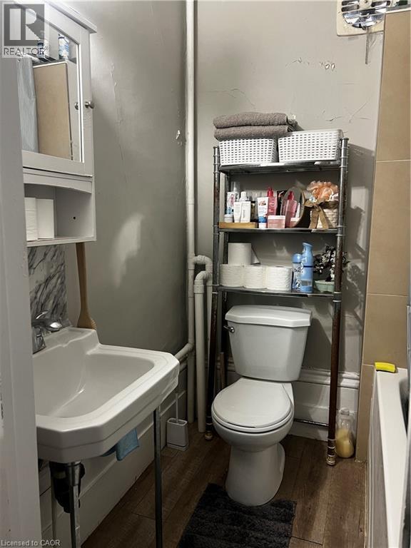 Bathroom featuring a wall-mounted sink, toilet, and shelving for storage