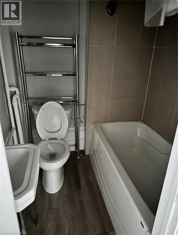 Bathroom featuring a bathtub, toilet, and a wall-mounted sink