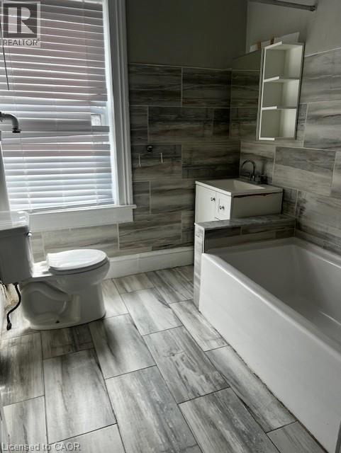 The bathroom features tile flooring, a bathtub, and a toilet