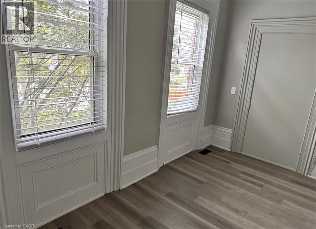 This space features light-toned walls, two windows with blinds, and wood-look flooring