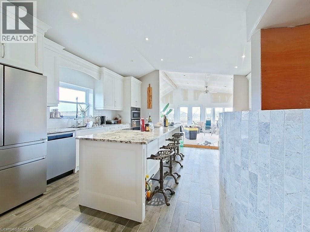 The kitchen features white cabinetry, stainless steel appliances, and a central island with a granite countertop