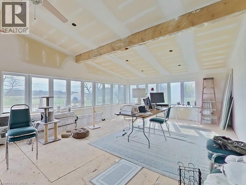 Expansive room featuring numerous windows, exposed ceiling beams, and a ceiling fan