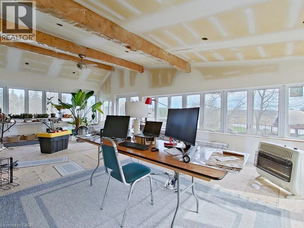 Spacious room featuring exposed wooden ceiling beams and extensive windows along two walls, providing ample natural light