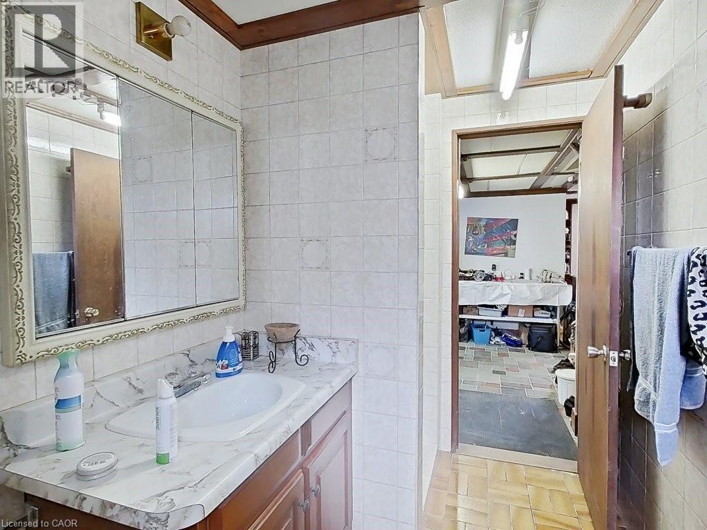 Bathroom with tiled walls and a vanity featuring a built-in sink, countertop, and wood cabinetry