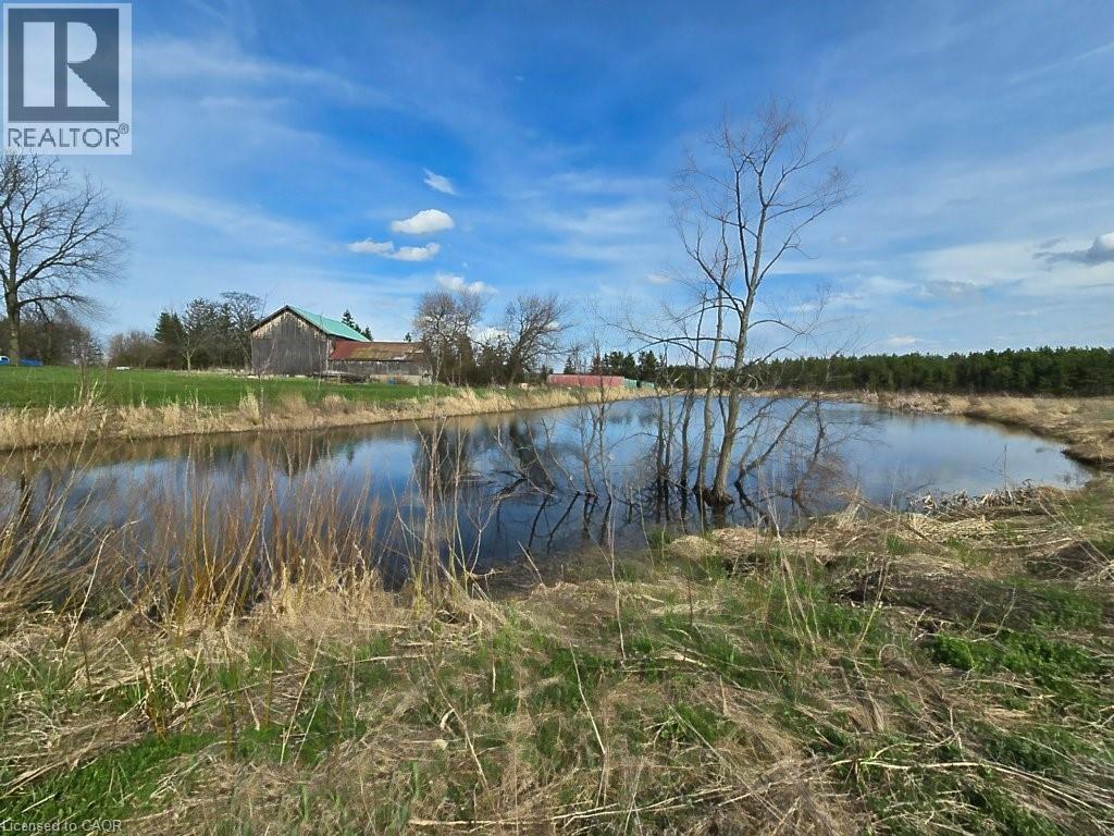 The property features a serene pond with reflections of the surrounding trees and clear blue sky