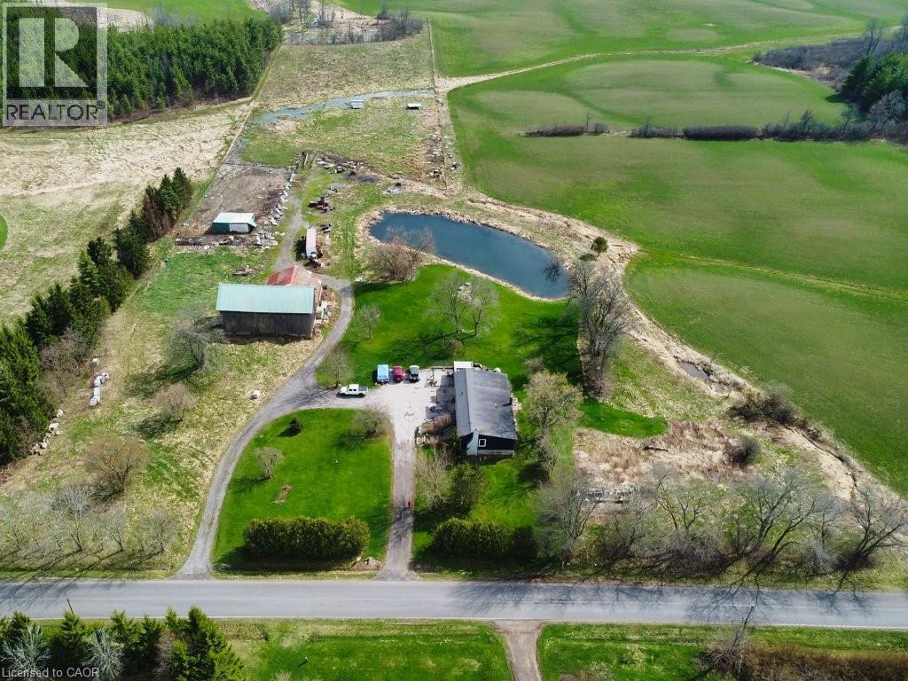 The property features a private pond, a substantial green lawn, and a paved driveway leading to the main residence