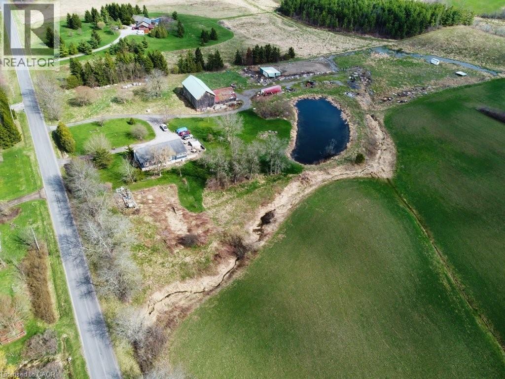This property features an extensive green landscape with a pond, a main building, and additional structures