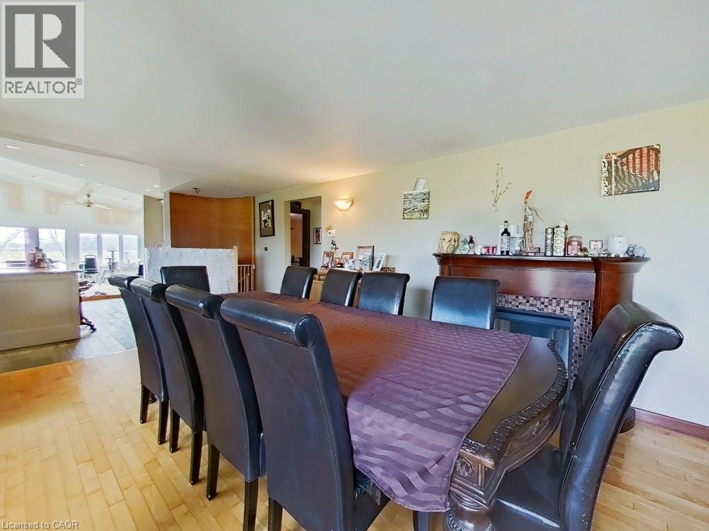 The dining area features light-toned hardwood flooring and a fireplace with a decorative tile surround and a wooden mantel