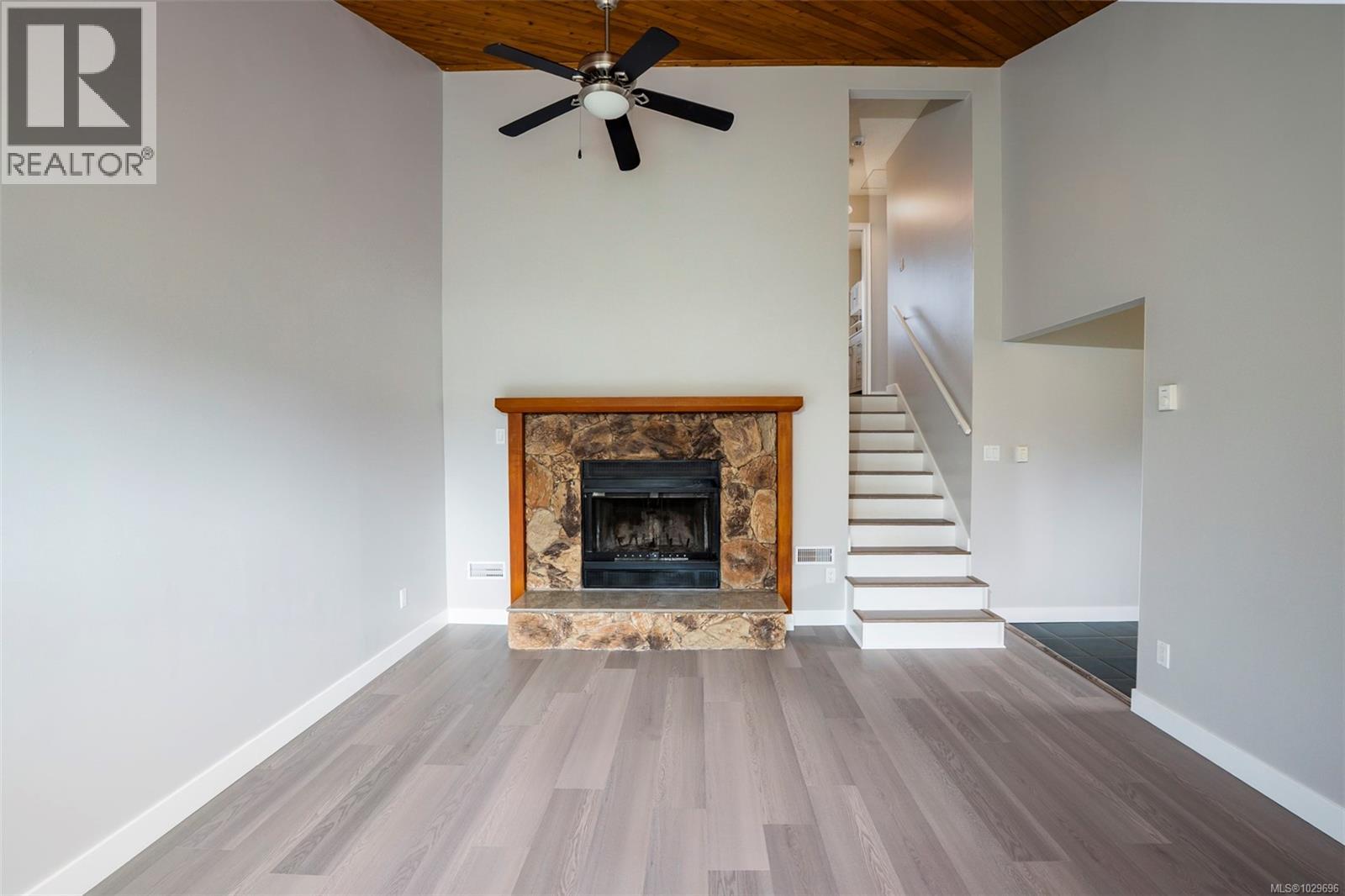 Wood burning fireplace with hearth & mantle, Ceiling fan. Stairs lead to bedrooms