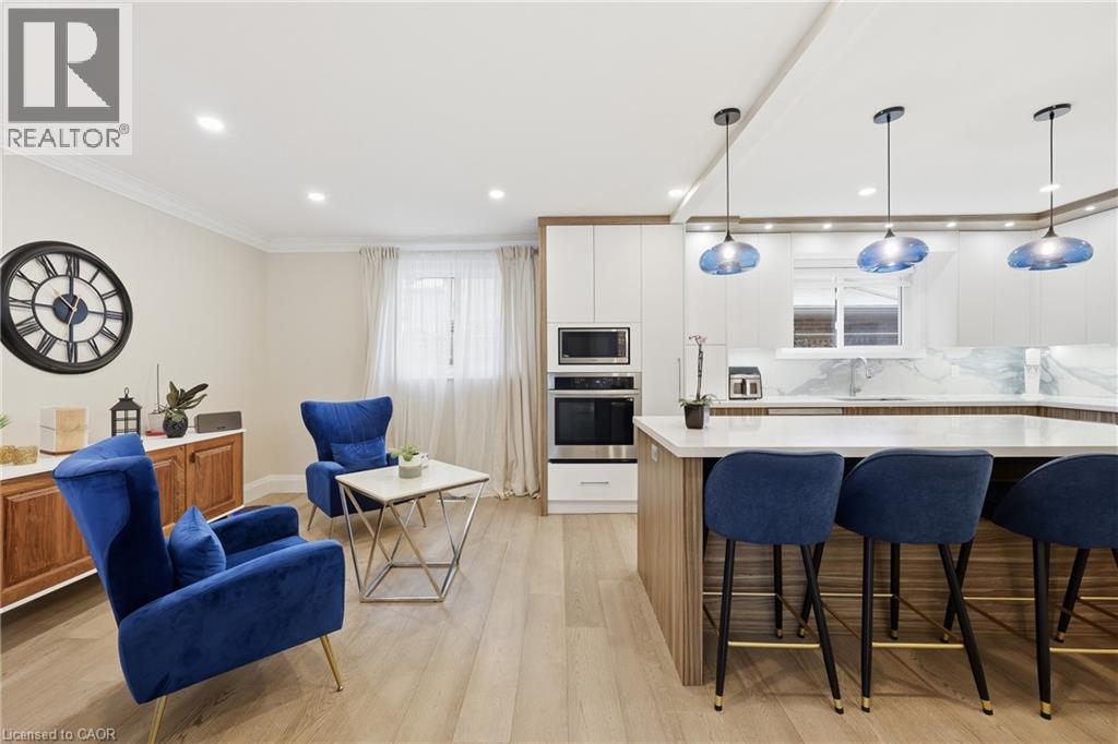 Two tone kitchen with light wood-type flooring, stainless steel appliances, decorative backsplash, a breakfast bar, and hanging light fixtures