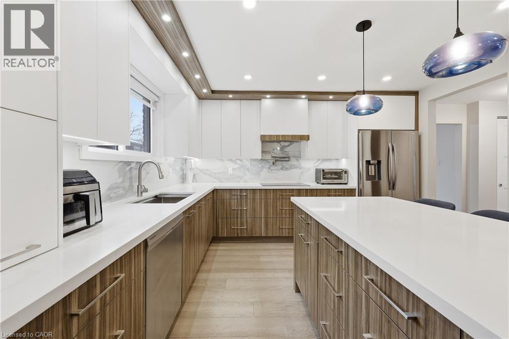 Dual tone kitchen with modern cabinets, two tone cabinets, stainless steel appliances, pendant lighting, and backsplash