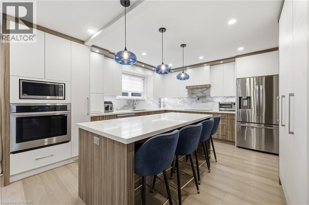 The kitchen features sleek white cabinetry, stainless steel appliances, and an expansive island with a light-colored countertop