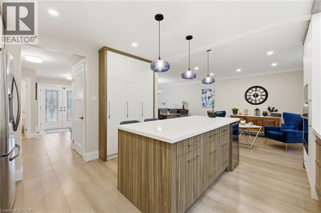 Kitchen with modern cabinets, a center island, light wood finished floors, decorative light fixtures, and stainless steel appliances