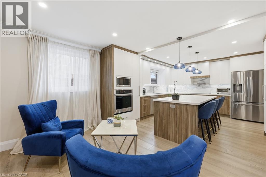 Kitchen with two tone cabinets, a kitchen island, light wood-style flooring, stainless steel appliances, and decorative backsplash