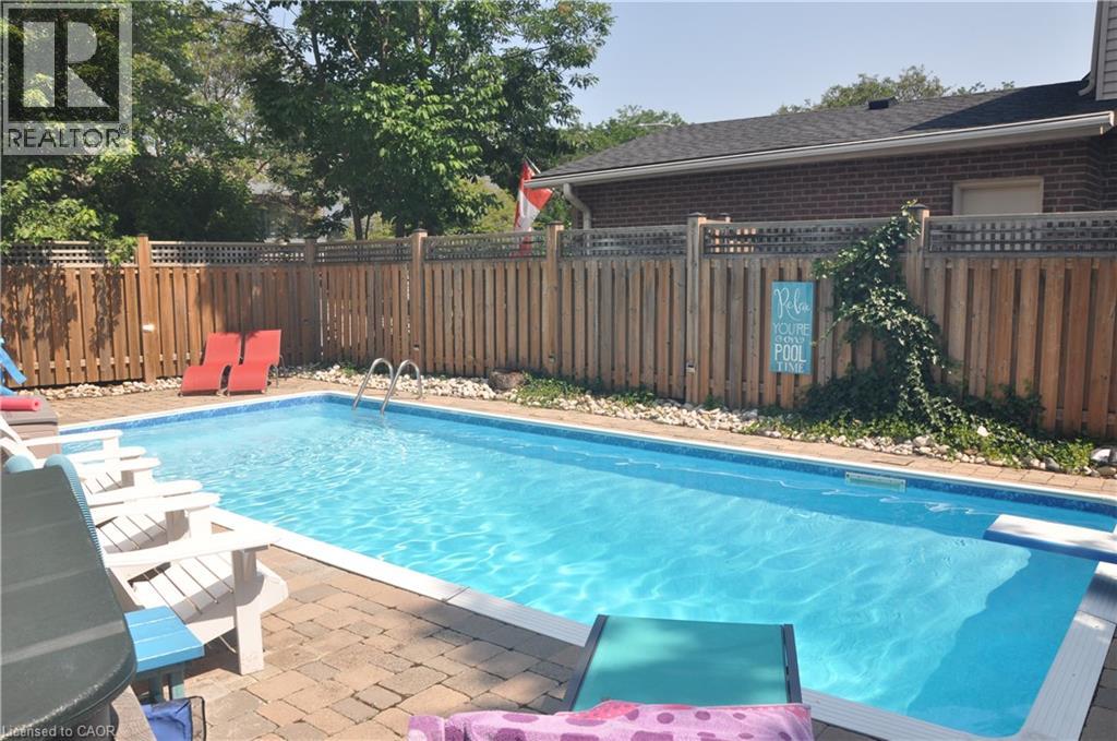 View of swimming pool with a fenced backyard, patio surround, and a diving board