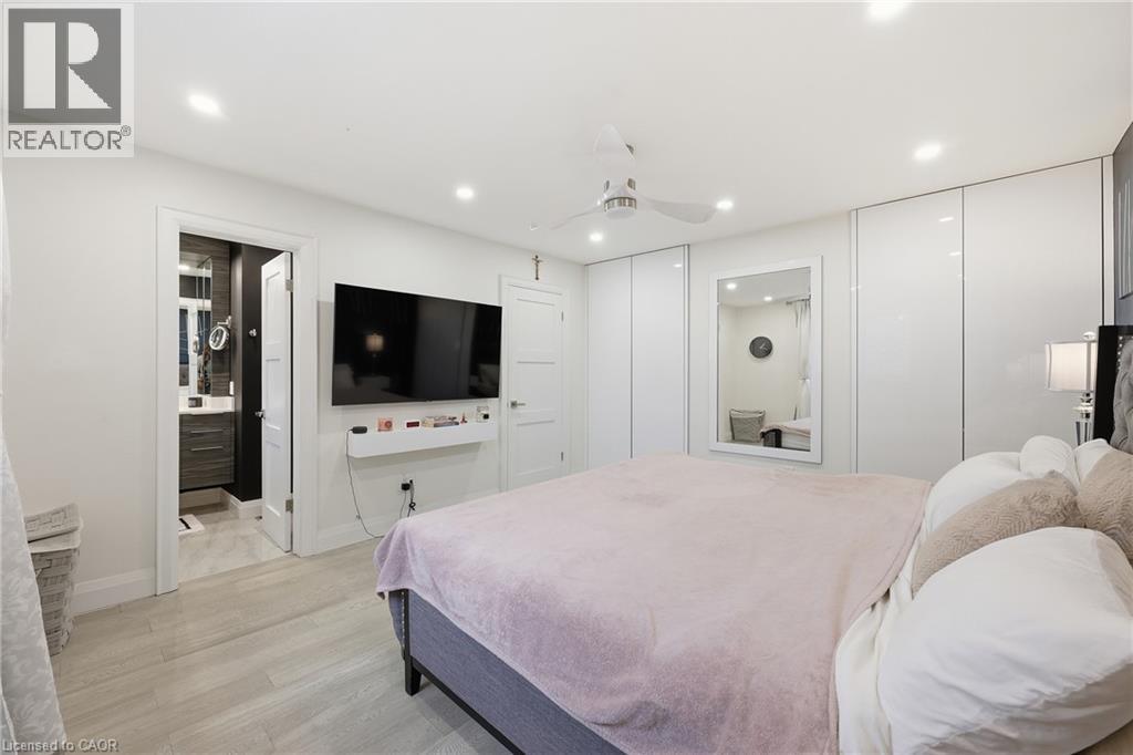Bedroom with light wood-style floors, multiple closets, recessed lighting, a ceiling fan, and ensuite bathroom