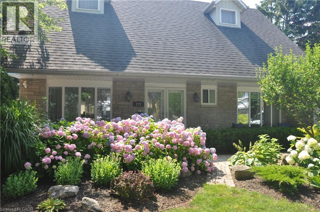 Rear view of house featuring roof with shingles and stone siding