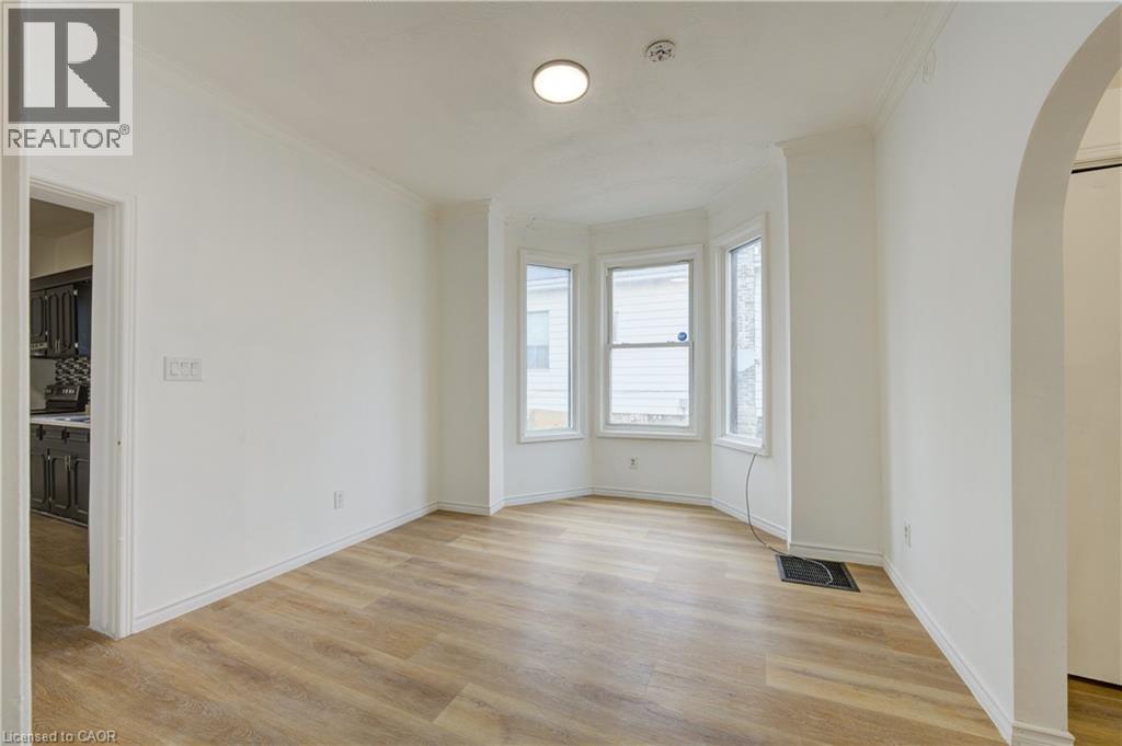 This room features light wood-style flooring, a bay window with three window panes, and an arched doorway