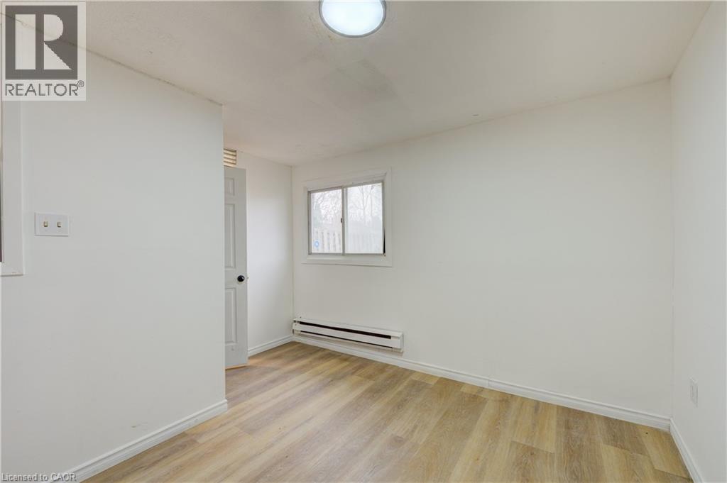 This room features light-toned wood-style flooring, a window providing natural light, and a baseboard heating unit