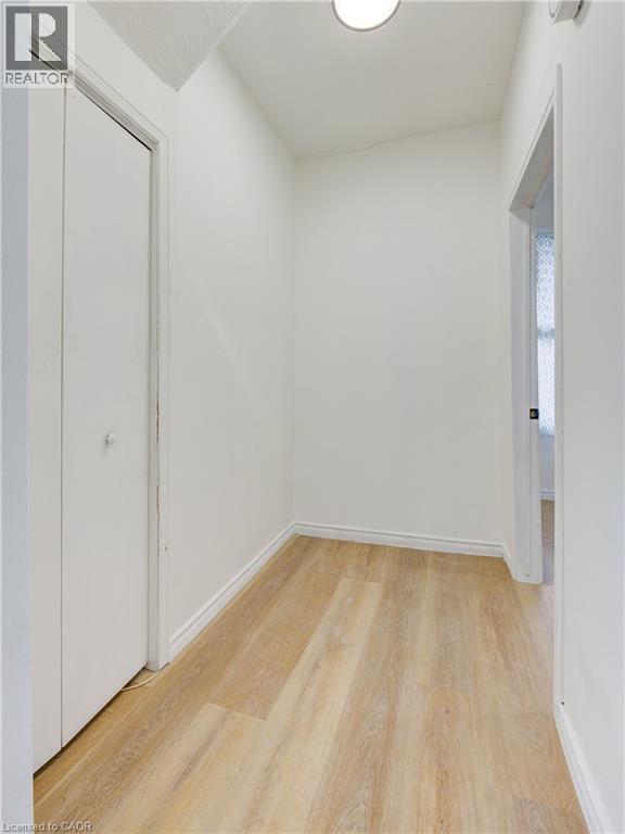 Hallway with light wood-style flooring, white walls, and a ceiling light fixture