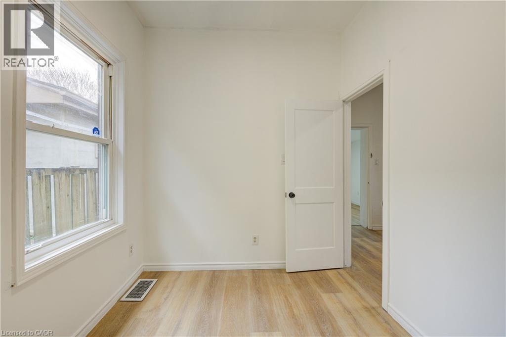 This room features light-colored walls, light wood-style flooring, a window, and a white door with a black doorknob