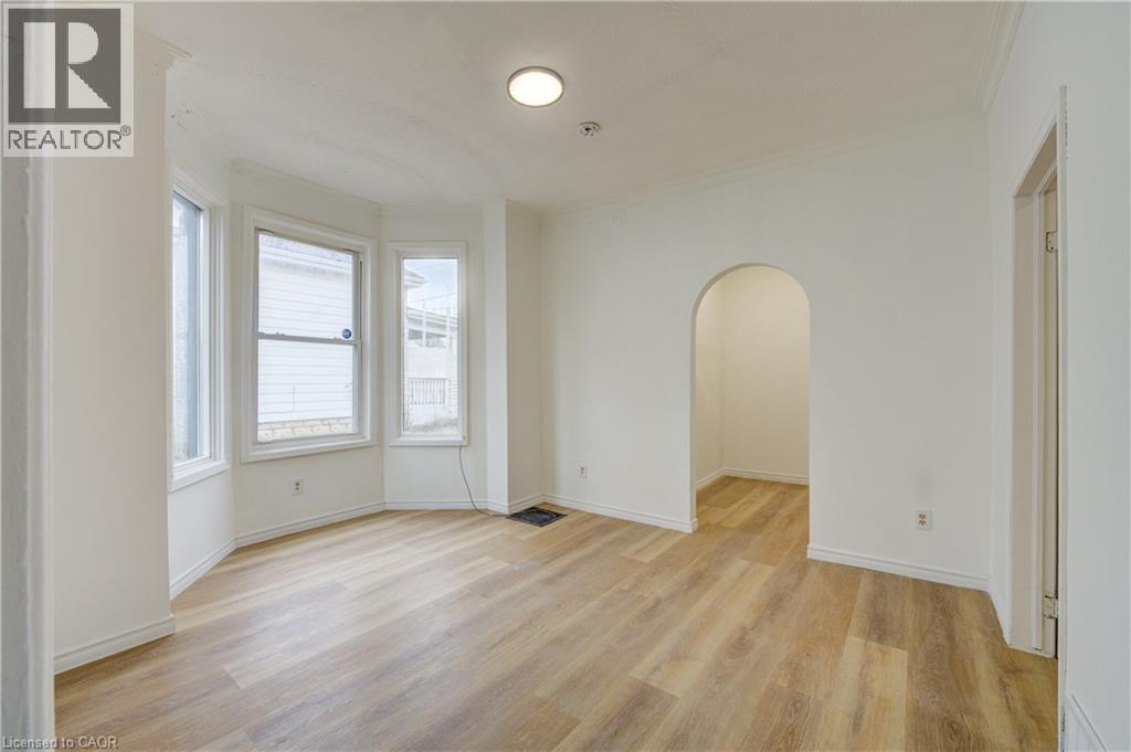 This inviting room features light-toned flooring, white walls, and a bay window that provides natural light