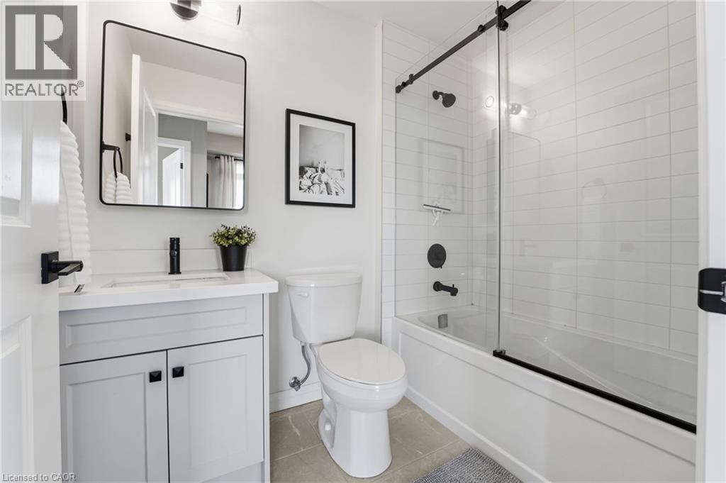 Bathroom with vanity, bath / shower combo with glass door, and light tile patterned flooring