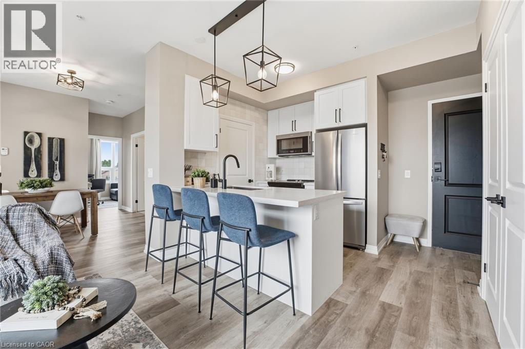 Kitchen featuring white cabinets, a kitchen bar, stainless steel appliances, a peninsula, and light wood-style floors