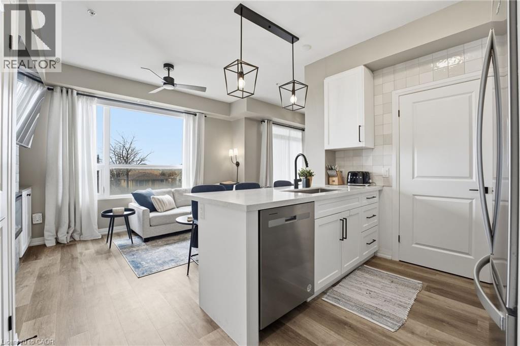 Kitchen with a peninsula, white cabinetry, a breakfast bar, stainless steel appliances, and hanging light fixtures