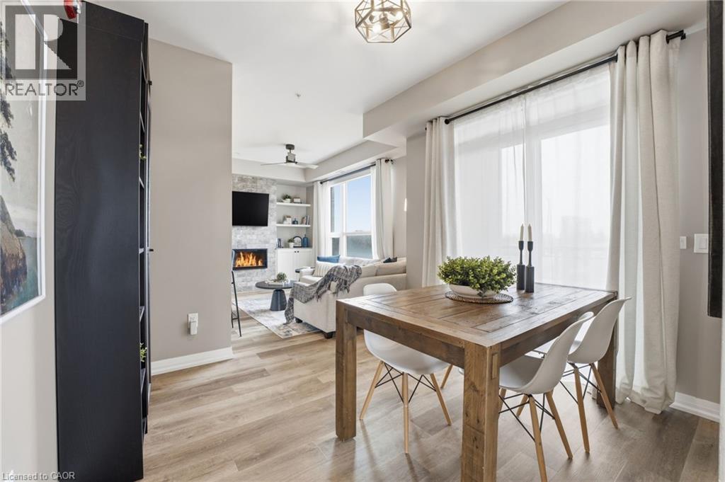 Dining space featuring light wood finished floors, a stone fireplace, and a ceiling fan